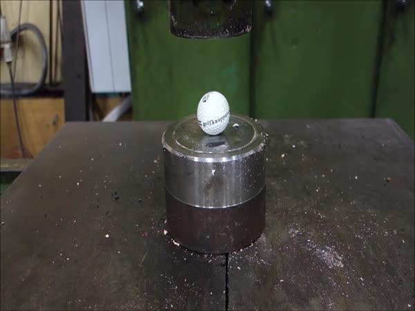       Golfový míček pod hydraulickým lisem      